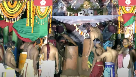 Servitors transferring Adhara Pana to earthen pot from the big brass container (Handa)